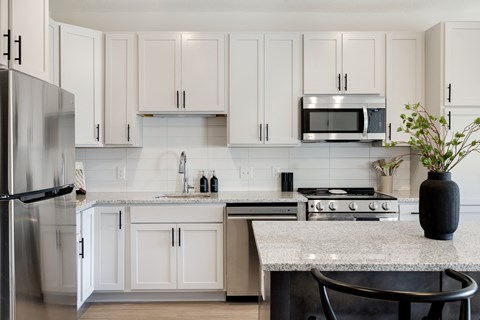 A kitchen with white cabinets and a granite countertop.