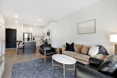A living room with a black leather couch and a white coffee table.
