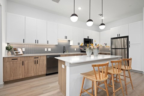 A kitchen with wooden chairs and a white island.