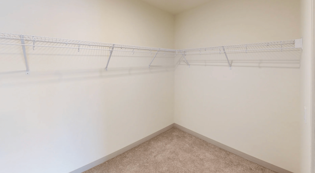 an empty closet with white walls and hanging racks