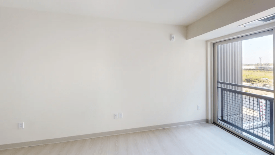 an empty living room with a large window and a balcony