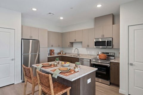 A kitchen with a table set for two and a refrigerator.