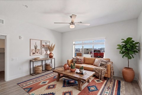 A living room with a brown sofa, a rug, and a ceiling fan.