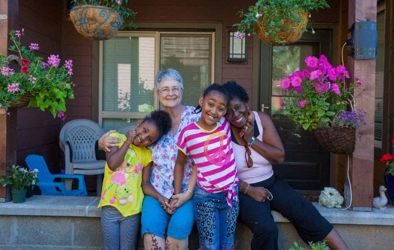 a woman sitting on a porch with three girls