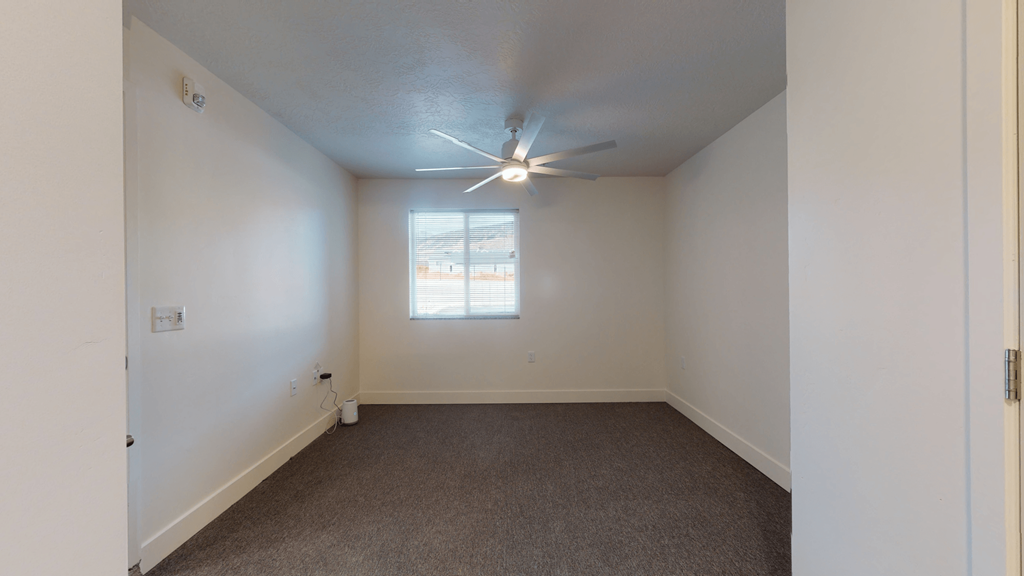 an empty living room with white walls and a ceiling fan