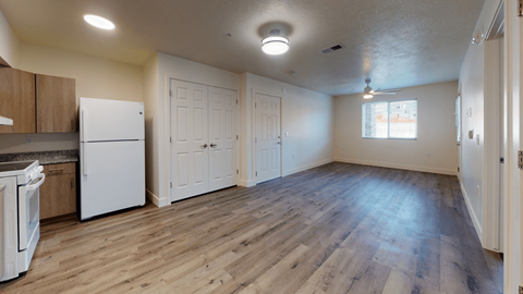 an empty kitchen and living room with white appliances and wood floors