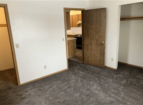 a bedroom with a door to a kitchen and a carpeted floor
