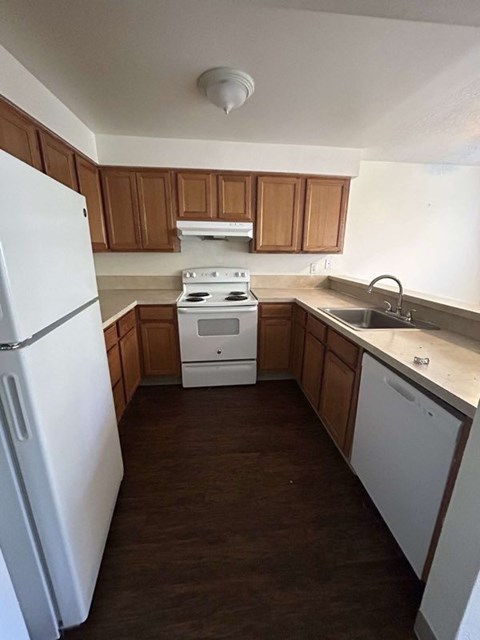 A white refrigerator stands in a kitchen with wooden cabinets.