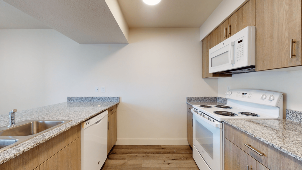 an empty kitchen with white appliances and granite counter tops
