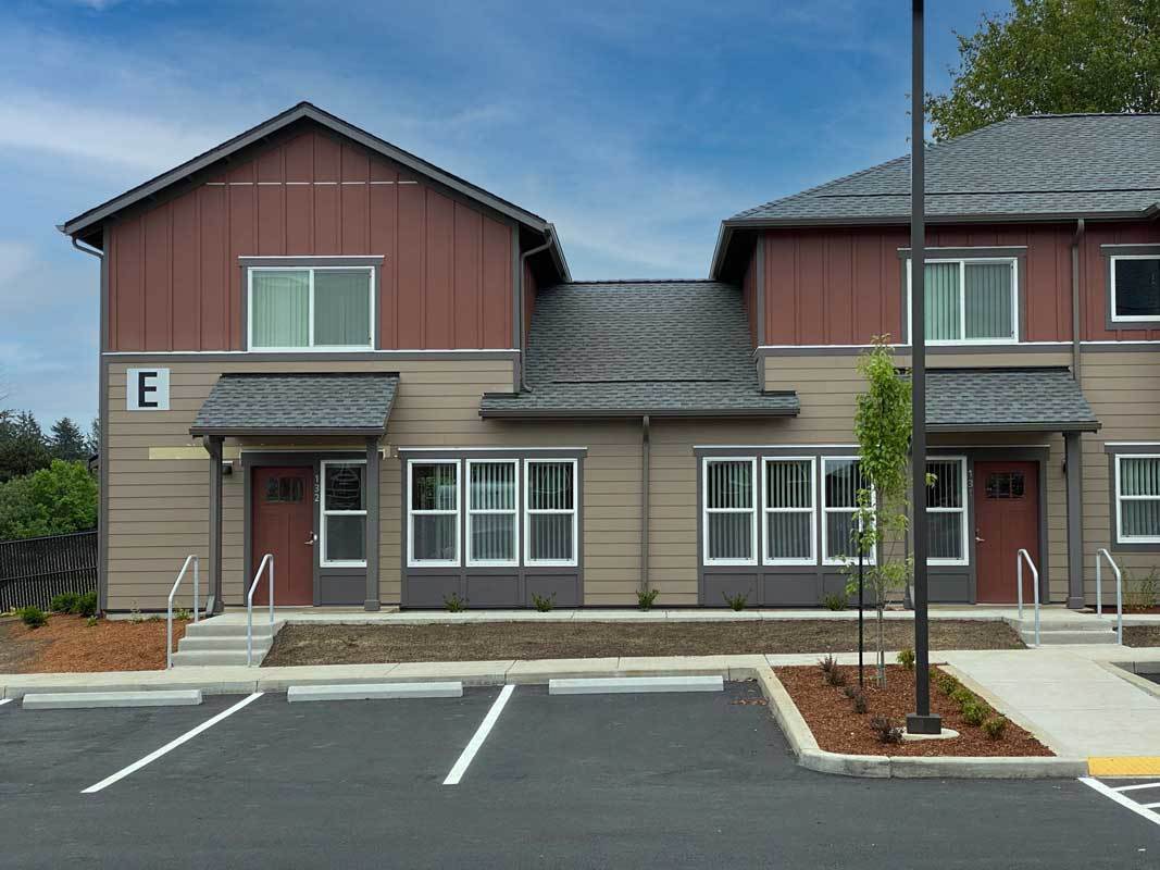 A two-story building with a parking lot in front.