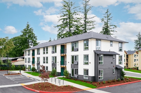 A modern apartment building with a parking lot in front.