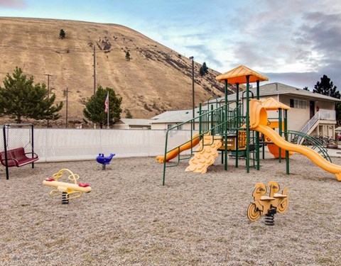 A playground with a yellow slide and a red bench.