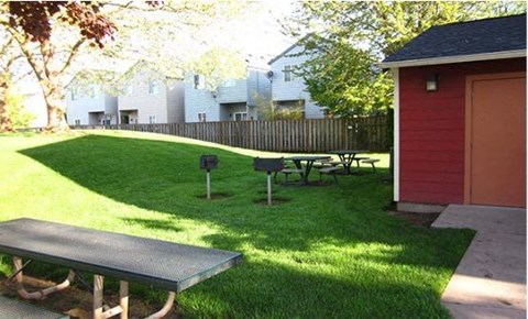 a backyard with a picnic table and a red shed