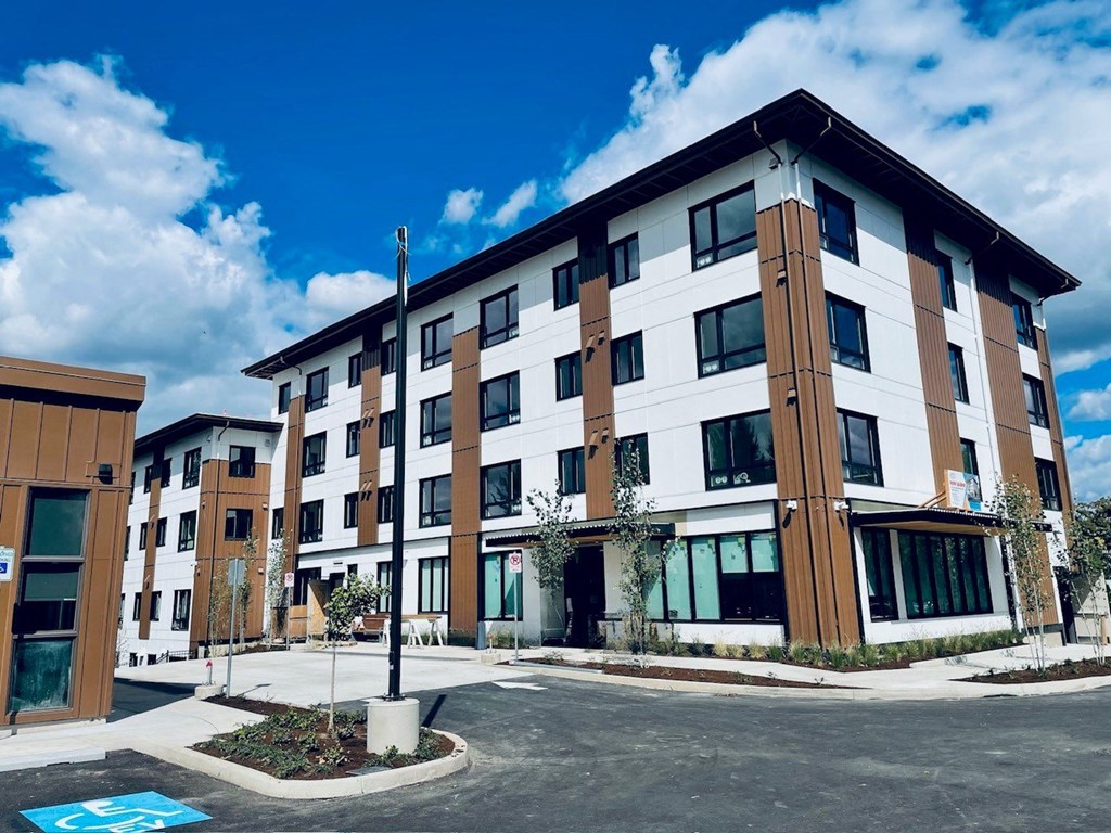 a building with a parking lot in the foreground and a blue sky in the background