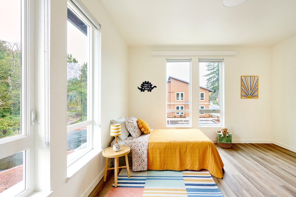 a bedroom with a yellow bed and two large windows