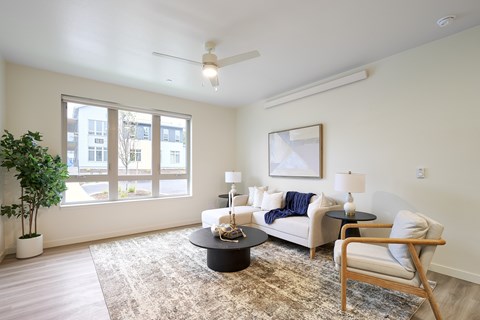 A living room with a white couch, a black coffee table, and a wooden chair.