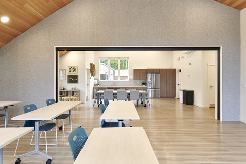A room with tables and chairs and a kitchen area.