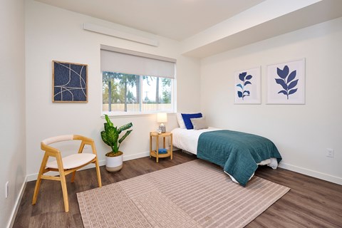 a bedroom with a bed and a chair and a window