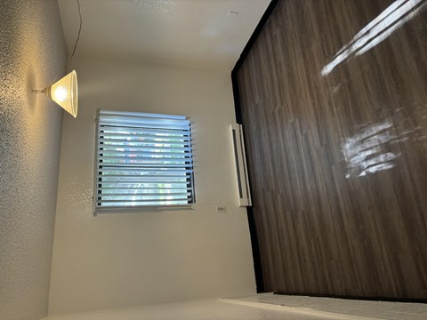 A room with a window covered by blinds and a wall-mounted air conditioner unit.