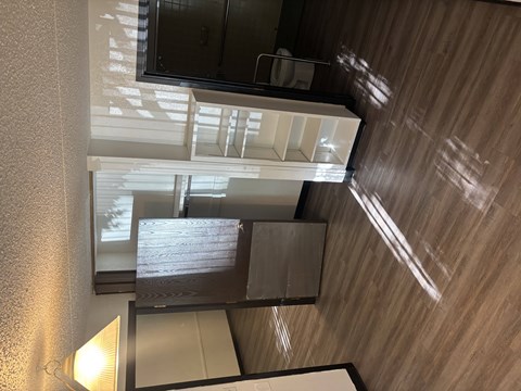 A mirrored wall reflects a room with a window.