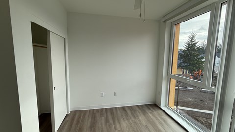 A room with a large window and wooden flooring.
