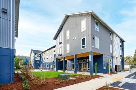 A modern building with a blue and grey exterior and a playground in front.