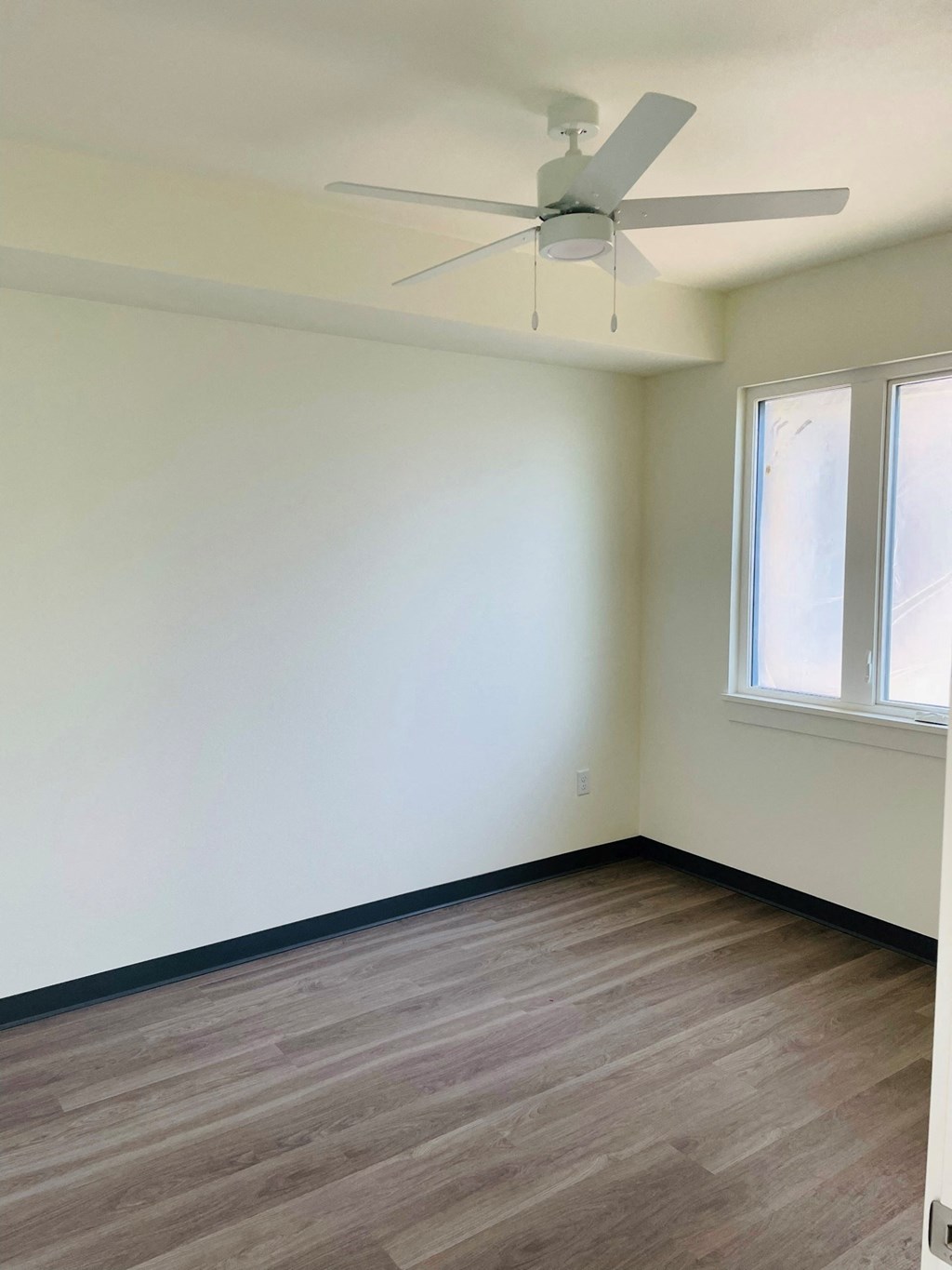 an empty room with a ceiling fan and two windows