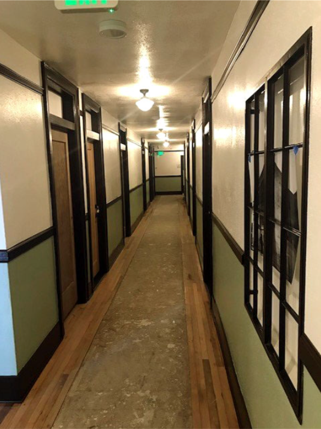 A long hallway with doors on the left and windows on the right.