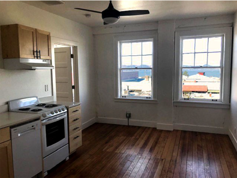 A kitchen with a stove top oven and a window overlooking a body of water.