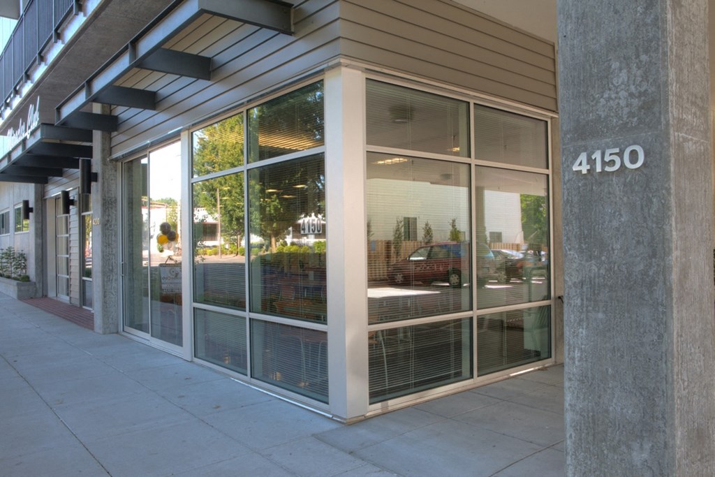 the front of a store with glass windows and a sidewalk