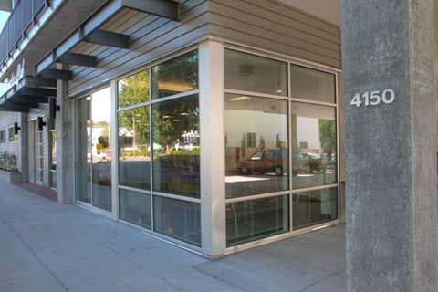 the front of a store with glass windows and a sidewalk