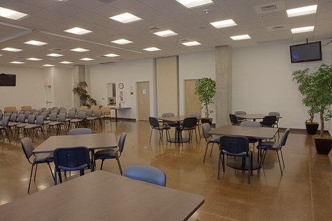 a multipurpose room with tables and chairs and a tv