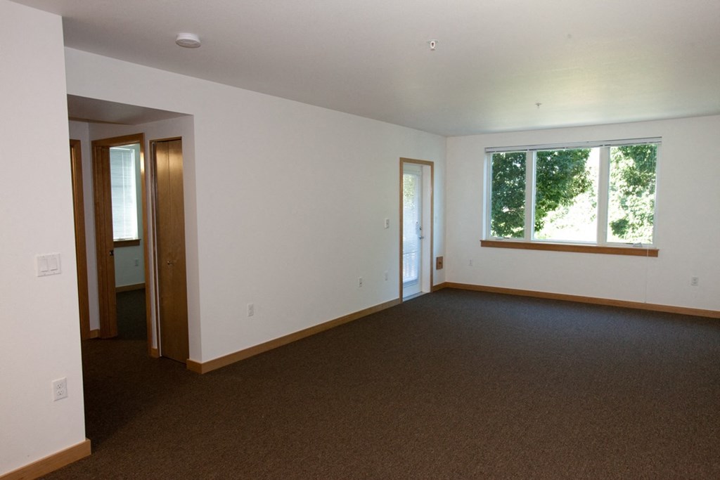 an empty living room with a window and a door