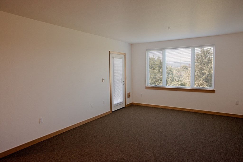 an empty living room with a window and a door
