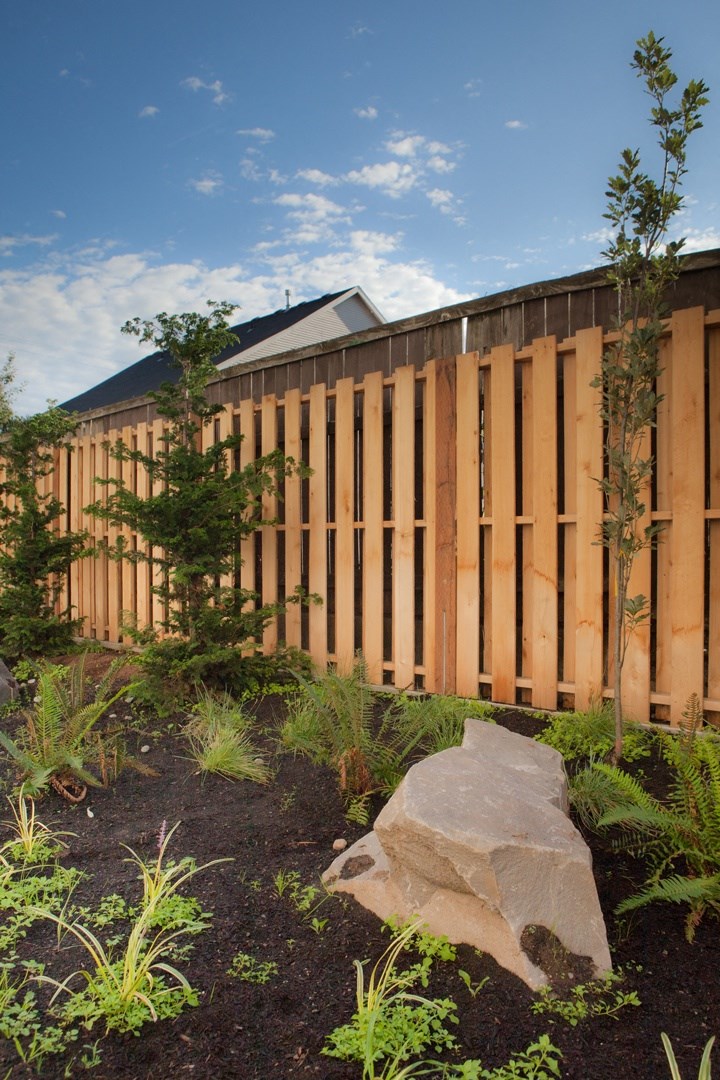 a garden in front of a building with a wooden fence