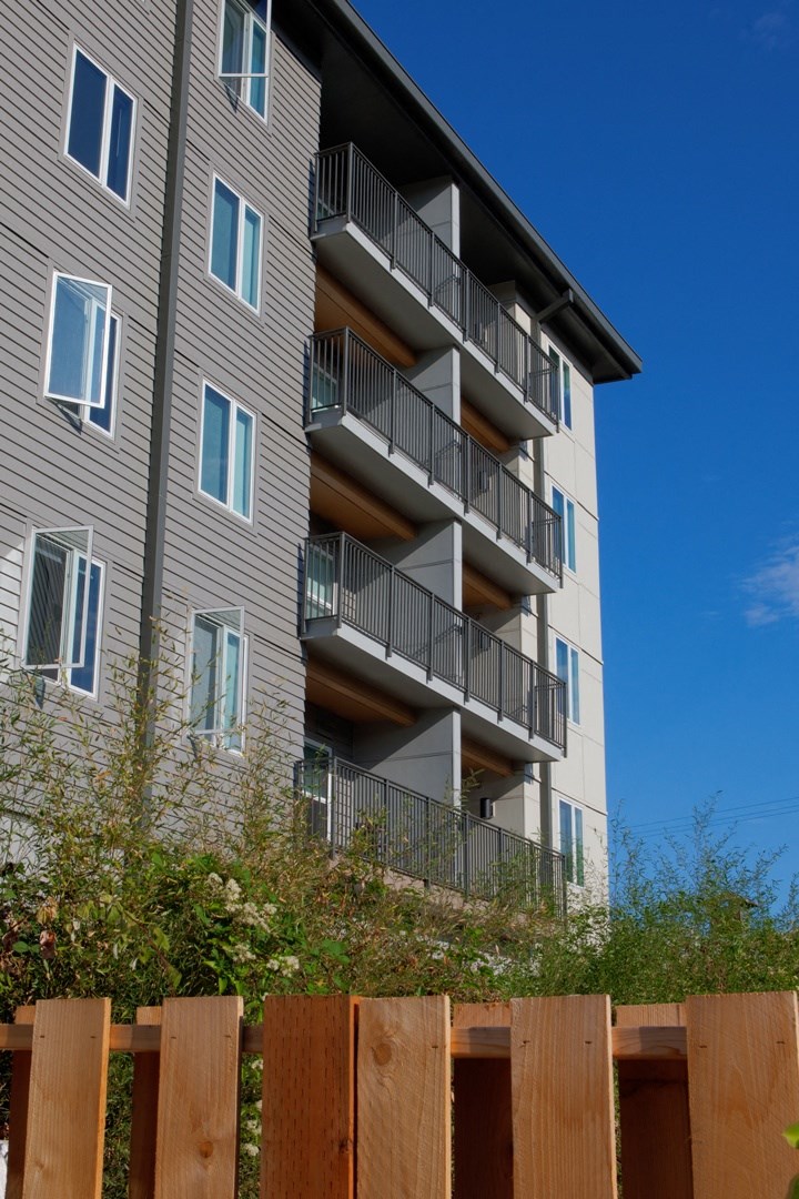 an apartment building with balconies and a wooden fence
