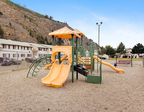 A playground with a yellow slide and a green structure.