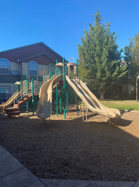 a playground with two sets of slides in front of a building