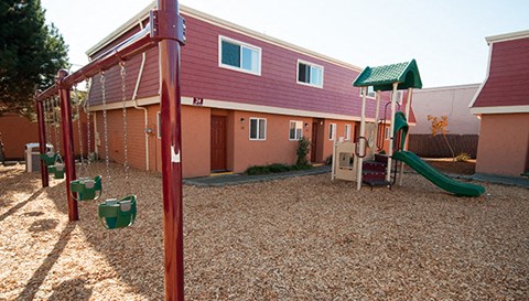 a playground in front of a house with a swing set