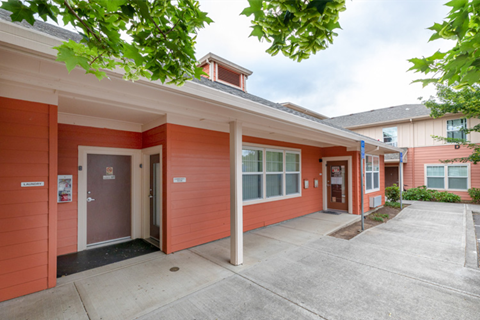 the front of a red building with a sidewalk and a door