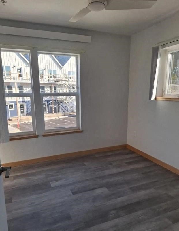 A room with a grey floor and a window overlooking a parking lot.