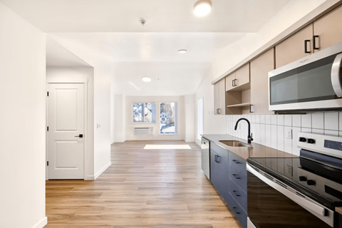 A kitchen with a white door and a black stove top oven.