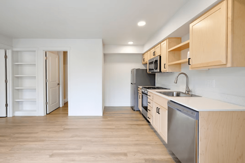 A kitchen with wooden cabinets and a stainless steel dishwasher.