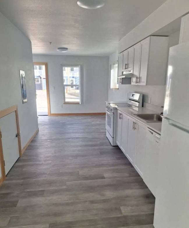 A kitchen with white cabinets and a grey floor.