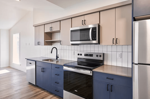 A kitchen with a black stove top oven and a black microwave above a sink.