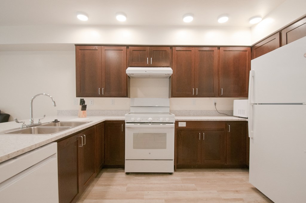 an empty kitchen with white appliances and wooden cabinets