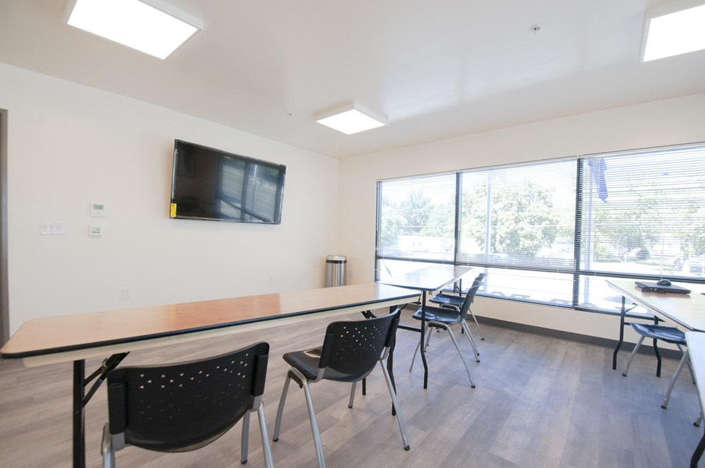 a conference room with tables and chairs and a television