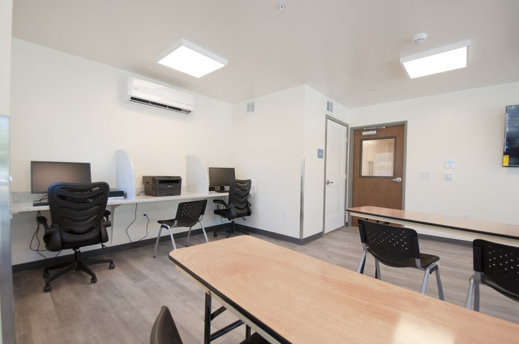 a room with desks and chairs and a table with a television