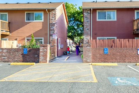 a group of people walking down a sidewalk in front of an apartment building