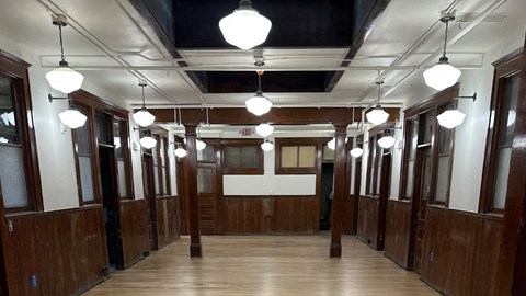 a row of wooden doors in a room with lights hanging from the ceiling